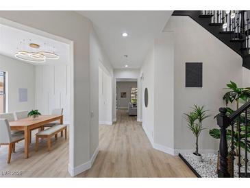 Bright entryway featuring modern light fixture, wood floors, and view of the dining area at 17 Winding Rd, Henderson, NV 89052