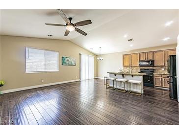 Spacious living room featuring hardwood floors and a ceiling fan, adjacent to the kitchen and dining area at 5079 Quiet Falls Ct, Las Vegas, NV 89141