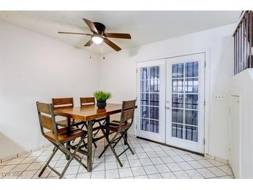 Bright dining room features a wooden table, four chairs, a ceiling fan and glass panel doors at 875 Rhinegold Way, Las Vegas, NV 89110
