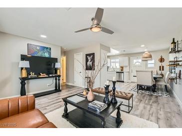 Bright living room with ceiling fan and view into dining area and kitchen with white cabinets at 445 Concord Way, Henderson, NV 89015