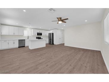 Open-concept living space features a ceiling fan, wood floors, and seamlessly connects the kitchen and living areas at 952 Balzar Ave, Las Vegas, NV 89106