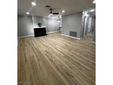 Spacious living room featuring ceiling fan, fireplace, and light wood flooring at 150 Greenbriar Townhouse Way, Las Vegas, NV 89121