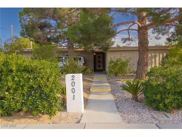 Charming home featuring mature trees, lush landscaping and a welcoming walkway to the front door at 2001 E Mcwilliams Ave, Las Vegas, NV 89101