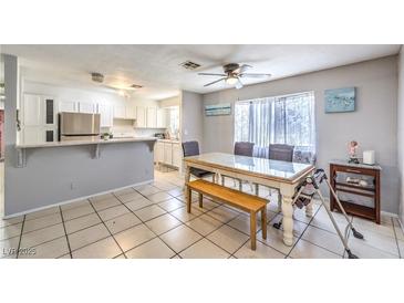 Bright dining area featuring tile floors, a ceiling fan, and a dining table with seating and an adjacent kitchen at 844 Balzar Ave, Las Vegas, NV 89106