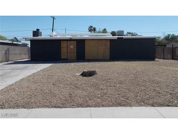 Exterior view of boarded up single story house and rock groundcover at 1912 Statz St, North Las Vegas, NV 89030