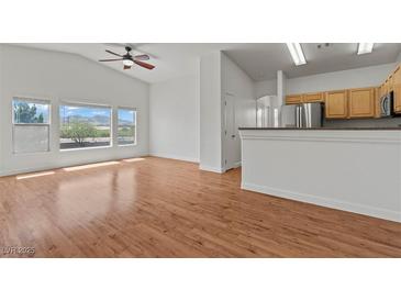 Bright living room features wood floors, large windows, ceiling fan, and an open floor plan at 2596 Lazy Saddle Dr, Henderson, NV 89002