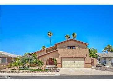 Charming stucco home with a two-car garage, palm trees, and colorful landscaping at 4475 Harmony Ct, Las Vegas, NV 89121