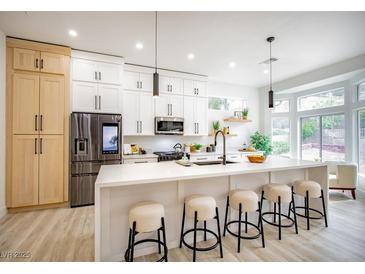 Bright kitchen features an island with seating, stainless steel appliances, modern cabinets, and a large window at 10025 Netherton Dr, Las Vegas, NV 89134
