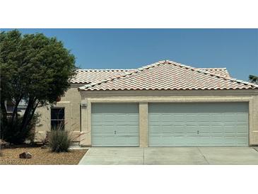 Beige house featuring a two-car garage and desert landscaping against a clear blue sky at 1902 Panther Pl, North Las Vegas, NV 89031