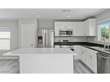 Modern kitchen with white cabinets, stainless steel appliances, and a quartz countertop island at 5116 Iron Crossing Ave, Las Vegas, NV 89131