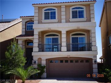 Inviting three-story home boasting a neutral stucco exterior, balcony, and an attached two-car garage at 5889 Thistle Meadow Ave, Las Vegas, NV 89139