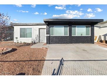Single story home with a mix of white and black brick exterior and easy to maintain gravel landscaping at 704 Slayton Dr, Las Vegas, NV 89107