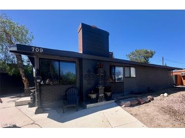 Charming single-story home featuring a dark exterior, landscaped yard, and a spacious driveway at 709 Evergreen Cir, Las Vegas, NV 89107