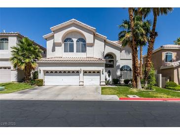 Beautiful two-story home featuring a three-car garage, manicured lawn and mature palm trees against a brilliant blue sky at 2090 Eaglepath Cir, Henderson, NV 89074
