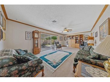 Cozy living room with floral furniture, ceiling fan, and sliding glass doors to the backyard at 22 Jade Cir, Las Vegas, NV 89106