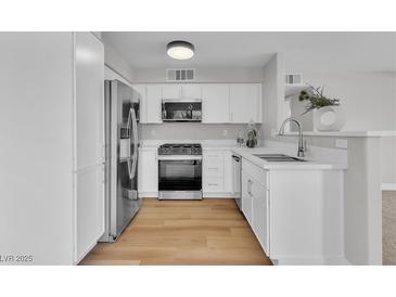 Bright kitchen featuring white cabinetry, stainless steel appliances, and light wood flooring at 5710 E Tropicana Ave # 2152, Las Vegas, NV 89122