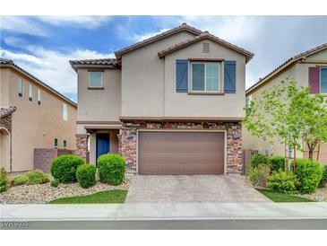 Two-story home featuring a stone veneer garage, blue shutters, desert landscaping, and a brick paver driveway at 6334 Orions Belt Peak St, North Las Vegas, NV 89031