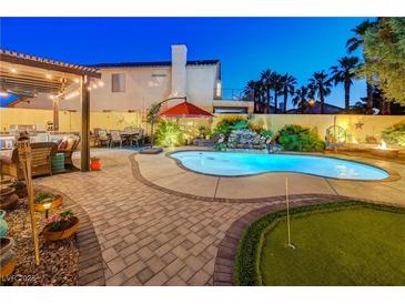 Inviting backyard pool with mature trees, a waterfall feature, an outdoor kitchen, and a putting green at 1028 Dodger Blue Ave, Las Vegas, NV 89123