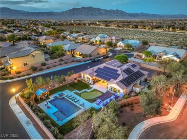 Stunning aerial view of a home with a pool, putting green, solar panels, and beautiful mountain views at 10319 Larkmead Ave, Las Vegas, NV 89149
