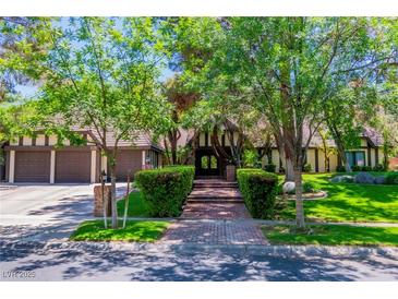 Charming home featuring mature trees, a brick walkway, and an attached three-car garage at 108 Quail Run Rd, Henderson, NV 89014