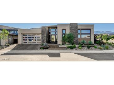 Contemporary home with desert landscaping, stone accents, and a sleek glass garage door at 5155 Rock Daisy Dr, Las Vegas, NV 89135