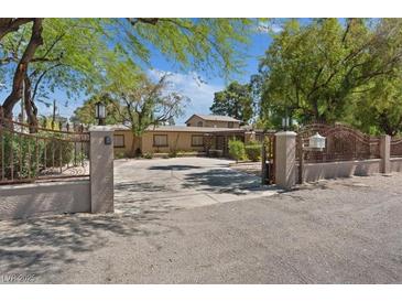 Gated entrance with mature trees and a circular driveway providing an estate-like feel at 5854 Sheila Ave, Las Vegas, NV 89108