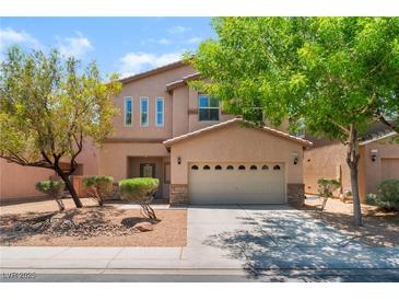 Charming two-story home with a two-car garage, desert landscaping, and mature trees at 6125 Paddleboat St, North Las Vegas, NV 89031
