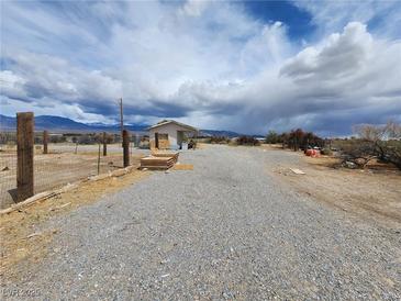 Desert property featuring a gravel driveway and small structure under a cloudy sky at 781 Buol Rd, Pahrump, NV 89048