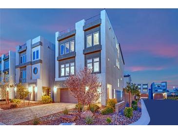 Modern three-story townhome with stucco facade and desert landscaping at dusk at 8178 Eaton Hill St, Las Vegas, NV 89113