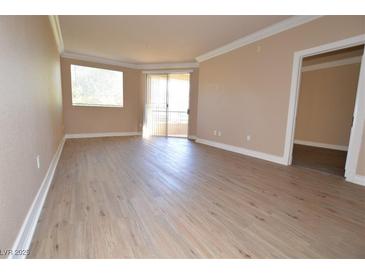 Bright living room featuring wood flooring, neutral walls, with a window and glass door leading to an outdoor space at 220 E Flamingo Rd # 116, Las Vegas, NV 89169