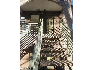 Exterior view of the staircase leading to the entrance of the property, featuring gray stairs and a neutral colored door at 7730 Secret Shore Dr # 207, Las Vegas, NV 89128