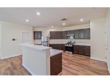 Open kitchen features dark cabinets, stainless steel appliances, and a breakfast bar at 2037 Brush Stroke St, Henderson, NV 89044