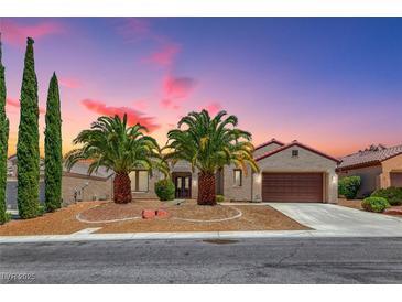 Charming single-story home with desert landscaping, palm trees, and a two-car garage under a colorful dusk sky at 2114 Twin Falls Dr, Henderson, NV 89044