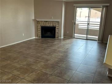 Inviting living room with fireplace and sliding door to balcony for natural light and fresh air at 6865 Tamarus St # 202, Las Vegas, NV 89119