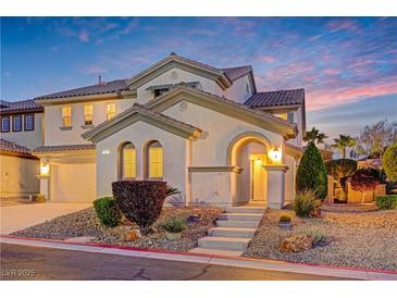 Inviting two-story home with arched entry, landscaping, and a charming facade at dusk at 733 Secret London Ave, Las Vegas, NV 89178