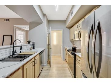 Updated kitchen features stainless steel appliances, a modern faucet, and light wood cabinets at 8000 Badura Ave # 1007, Las Vegas, NV 89113