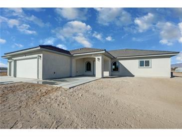New construction home featuring stucco exterior, an attached garage and new concrete porch in an undeveloped lot at 1580 S Tiptop Trl, Pahrump, NV 89048