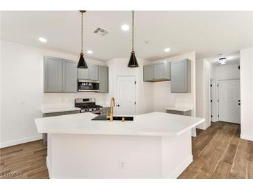 Bright kitchen featuring a large island, pendant lighting, stainless steel appliances, and wood-look floors at 4779 Straight Flush Dr # 103, Las Vegas, NV 89122