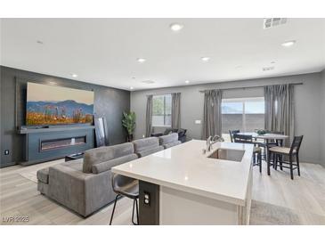 Open-concept living room features a modern fireplace, TV and a spacious gray sectional couch at 9714 Harper Edge St, Las Vegas, NV 89143