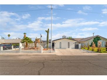 Charming single-story home featuring desert landscaping, a white fence, and a long driveway at 4301 Fortune Ave, Las Vegas, NV 89107