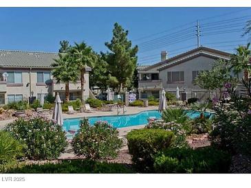 Community pool with chairs and tables, and lush landscaping surrounding the area at 5710 E Tropicana Ave # 2178, Las Vegas, NV 89122