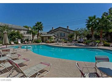 Inviting community pool with lounge chairs and lush palm trees offers a relaxing outdoor space for residents at 5710 E Tropicana Ave # 2178, Las Vegas, NV 89122