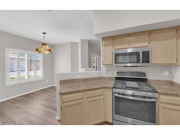 Bright kitchen featuring stainless steel appliances, light wood cabinets, and a stylish pendant light fixture at 6480 Annie Oakley Dr # 112, Las Vegas, NV 89120