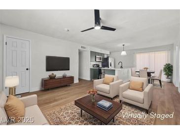 Bright, staged living room with modern furnishings, ceiling fan and seamlessly flowing into a kitchen with island seating at 728 Carpenter Dr, Las Vegas, NV 89107