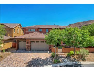 Beautiful two-story home with a three-car garage, terracotta roof, and lush landscaping at 10433 Ember Rose Ave, Las Vegas, NV 89135