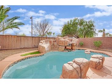 Backyard pool area featuring a rock waterfall and slide with light blue water at 3221 Birdwatcher Ave, North Las Vegas, NV 89084