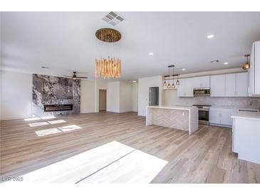 Bright and spacious living room featuring wood floors, a modern fireplace, and contemporary lighting at 5653 Artesia Lake Ct, Las Vegas, NV 89118