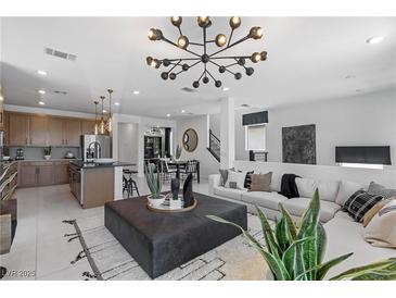 Bright living room featuring modern lighting, stylish decor, and an open floor plan to the kitchen and dining area at 7977 Texas Hills St, Las Vegas, NV 89113