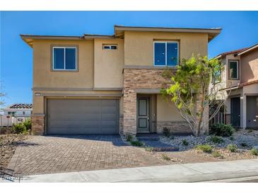 Two-story home featuring stacked stone accents, a gray two-car garage, and desert landscaping at 9588 Archer Peak Ct, Las Vegas, NV 89143