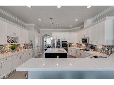 A spacious kitchen featuring white cabinets, quartz countertops, stainless steel appliances, and a stylish backsplash at 6131 Rio Vista St, Las Vegas, NV 89130